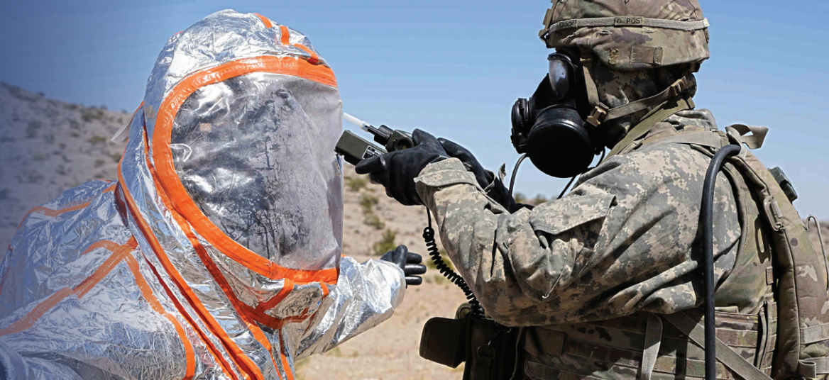 Military member in mask uses a radiation testing device on person in protective, anti-nuclear radiation suit